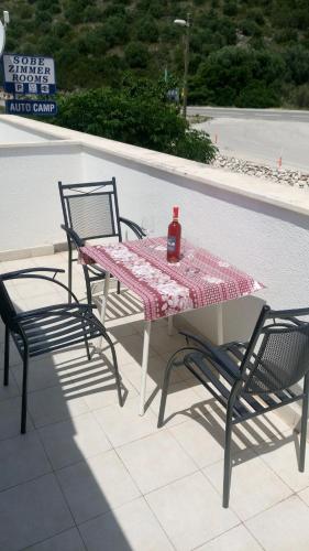 a table with two chairs and a bottle of wine on it at Guesthouse Budima in Banići