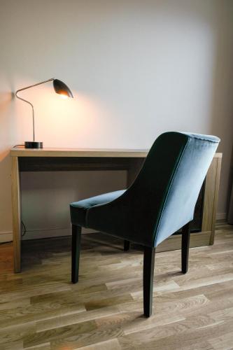 a chair sitting in front of a desk with a lamp at Quality Hotel Augustin in Trondheim