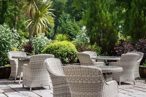 a group of wicker chairs and tables in a garden at Auchrannie Resort in Brodick