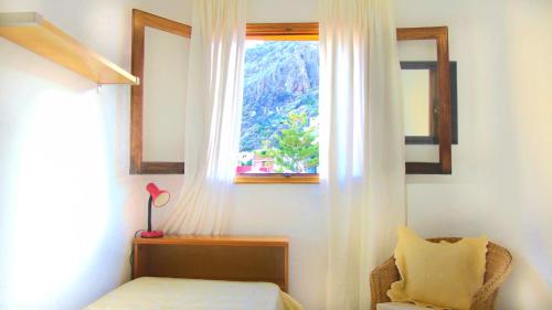 Un dormitorio con una cama y una ventana con una silla. en Apt. Lourdes, close to the Teresitas & Anaga, en San Andrés