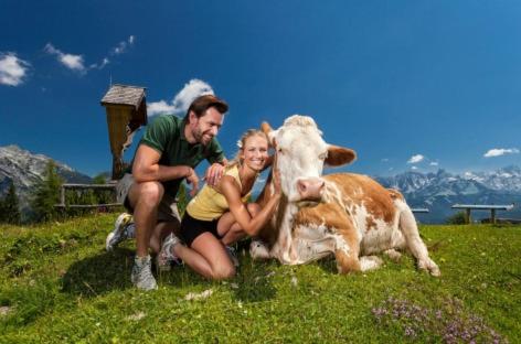 a man and woman posing with a cow on a field at Appartements Haus Bergland in Sankt Martin am Tennengebirge