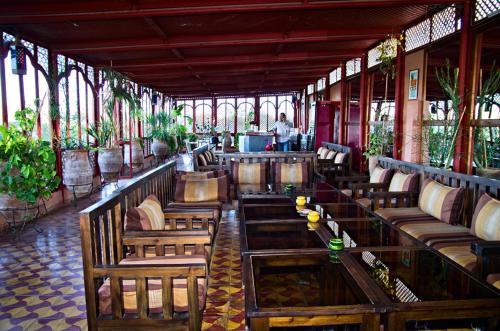 a restaurant with wooden tables and chairs and windows at Ryad de Vignes " Le Val d'Argan " in Ounara