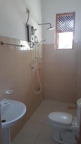 a bathroom with a shower and a toilet and a sink at Sandy Beach Hotel in Arugam Bay