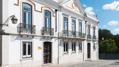 ein weißes Gebäude mit Fenstern und Balkonen darauf in der Unterkunft Palacete da Real Companhia do Cacau - Royal Cocoa Palace in Montemor-o-Novo