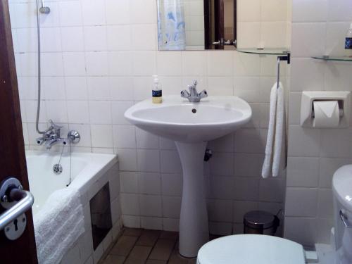 a white bathroom with a sink and a toilet at Kozmos in Clarens