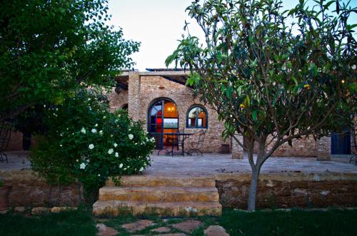 a stone house with a table and a tree at Ryad de Vignes " Le Val d'Argan " in Ounara