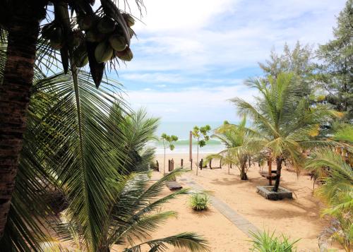 a sandy beach with palm trees and the ocean at Sandy Beach Hotel in Arugam Bay