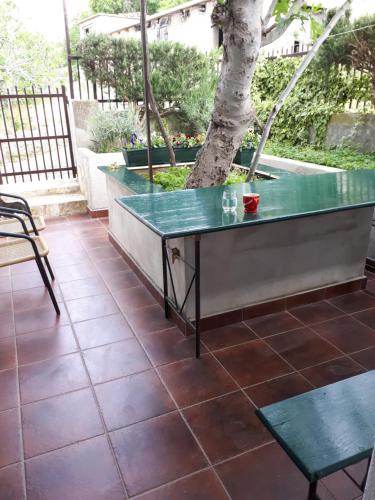 a green table on a patio with a tree at Luminaria Solis Vacation Home in Rogoznica