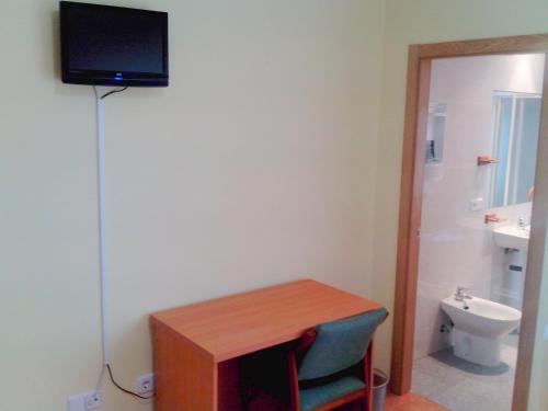 a room with a desk with a television and a toilet at Hotel RC Ramon y Cajal in Cuenca