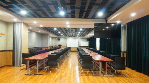 a conference room with tables and chairs and a screen at Nostalgia Hotel Tianjin Binhai Tanggu 时光漫步酒店天津滨海塘沽站店 Free fresh ground coffee,Free laundry service in Tianjin