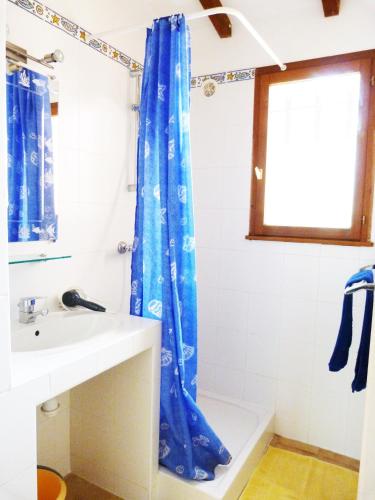 La salle de bains est pourvue d'un rideau de douche bleu et d'un lavabo. dans l'établissement A Suarticcia, à Pinarellu