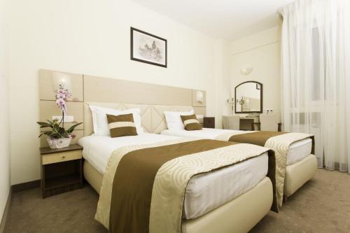 ein Hotelzimmer mit 2 Betten und einem Spiegel in der Unterkunft Grand Hotel Coroana in Bistriţa