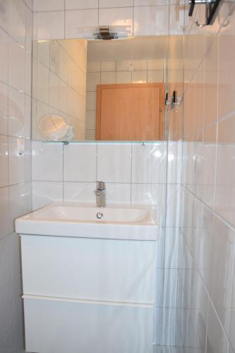 a white bathroom with a sink and a mirror at Appartement Stichauner in Tschöran