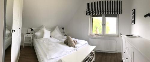 Tümlauer KoogにあるAppartements unter Reetの白いベッドルーム(ベッド1台、窓付)