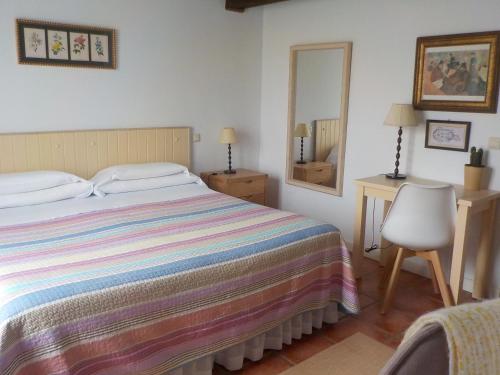 a bedroom with a bed and a desk and a mirror at Posada Tresvalle in Ubiarco