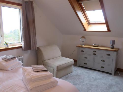 a bedroom with a bed and a chair and a mirror at Orasaidh Apartment in Stornoway