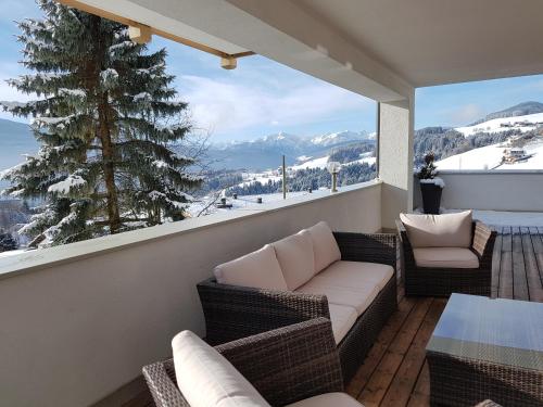 a balcony with a couch and chairs and a large window at Falkensteiner Hotel & Spa Sonnenparadies in Terento