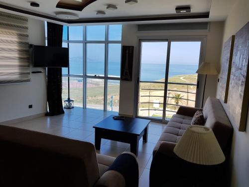 een woonkamer met een bank en uitzicht op de oceaan bij Fnideq Seaside Apartment in Fnidek