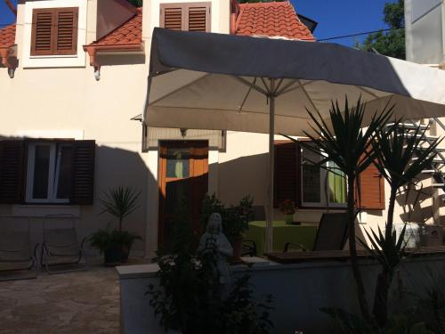 een wit huis met een paraplu ervoor bij Guesthouse Kresic in Split