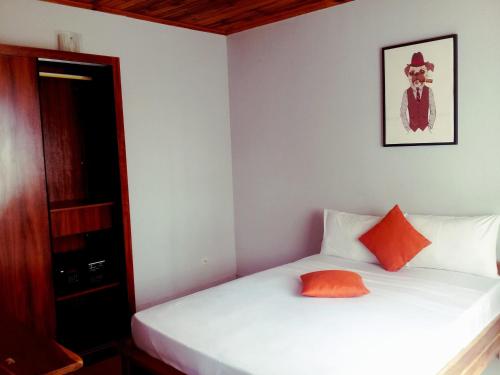 New Park Resort في ماهاجانجا: غرفة نوم بسرير ابيض ومخدة برتقال