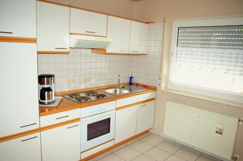 a kitchen with white cabinets and a sink and a window at fewogriebelschied in Griebelschied
