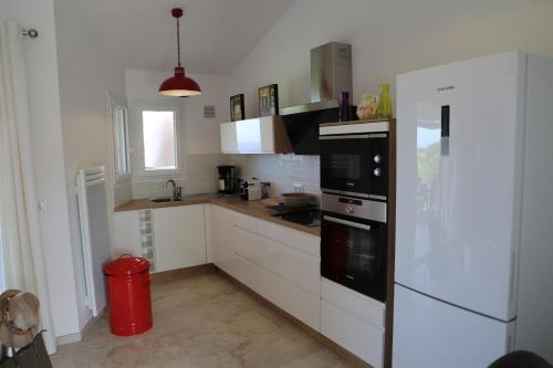 a kitchen with white cabinets and a black refrigerator at Résidence les Hameaux de Bocca del Oro in Porto-Vecchio