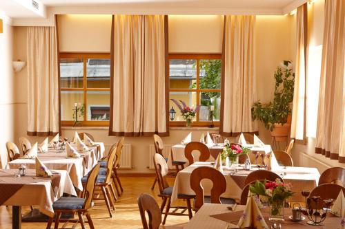 un restaurant avec des tables blanches, des chaises et des fenêtres dans l'établissement Gasthaus Stefaner, à Feistritz im Rosental
