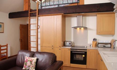 a kitchen with a loft bed and a couch in a room at Budleigh Farm Cottages in Moretonhampstead