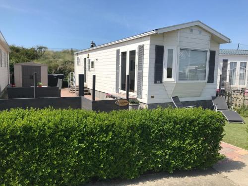 a white tiny house with a patio and a yard at Blauwe Zeedistel in IJmuiden