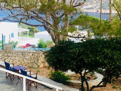 two blue chairs and a tree next to a stone wall at House in Kamares - Sifnos in Kamarai