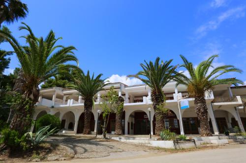 ein großes weißes Gebäude mit Palmen davor in der Unterkunft Maison La Mer in Agia Paraskevi