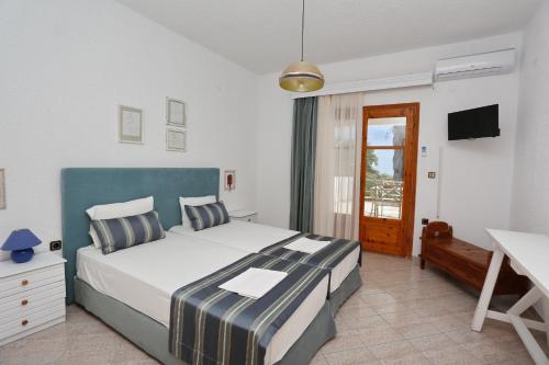 a bedroom with a bed and a desk and a television at Maison La Mer in Agia Paraskevi