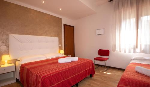 a bedroom with two beds and a red chair at Hotel Nazionale in Lido di Jesolo