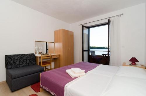 1 dormitorio con 1 cama, 1 silla y 1 ventana en Apartments Anica en Sobra