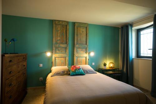 une chambre avec un grand lit aux murs verts dans l'établissement Le Mas Saint Philippe, à Jonquières