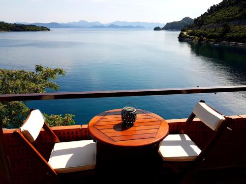 a table and chairs with a view of the water at Apartments Anica in Sobra
