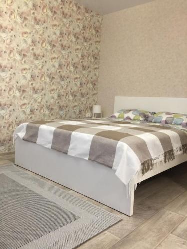 a bedroom with a bed with a blanket on it at Apartment Deluxe on Krasnopresnenskaya in Volgograd