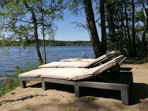 grupa łóżek siedzących na brzegu jeziora w obiekcie Antinkallio Lakeside Cape w mieście Lahti