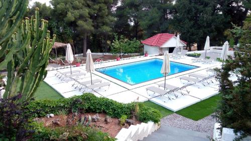 an image of a swimming pool with chairs and umbrellas at Pessada Bay Studios and Apartments in Pesádha