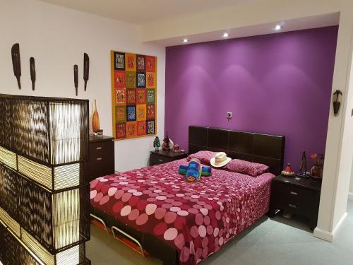 una camera da letto con un letto con una parete viola di Sylvias art studio apt a Ayia Napa