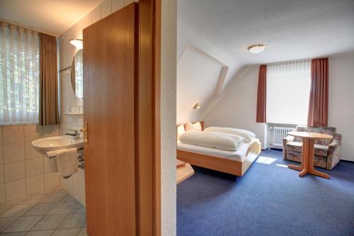 ein Schlafzimmer mit einem Bett und ein Badezimmer mit einem Waschbecken in der Unterkunft Gasthaus zum Hirschen in Oberrimsingen