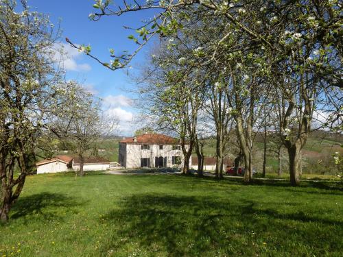 a house in a field with trees in the foreground at Domaine de calbiac in Dolmayrac