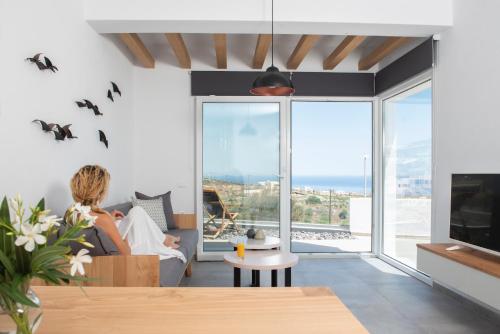 a woman sitting in a living room with a view of the ocean at Valery Suites in Fira