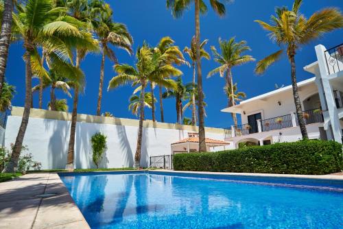 a swimming pool in front of a house with palm trees at La Posada Del Tepeyac in La Paz
