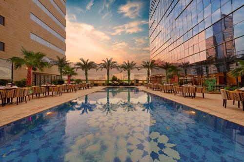 a hotel pool with tables and chairs in front of a building at Makkah Al Aziziah in Makkah