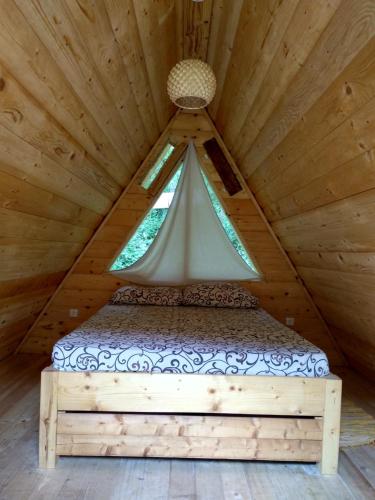 a bed in a wooden room with a window at Camp Vrbas in Rekavice
