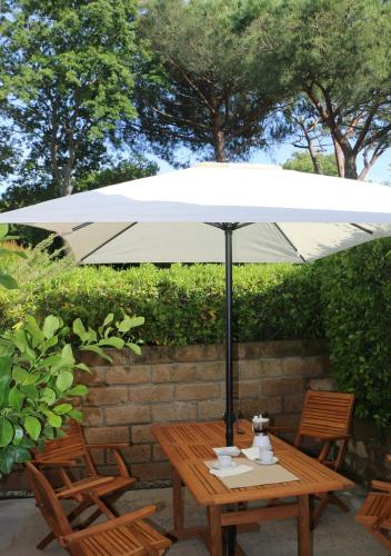 a wooden table with an umbrella and two chairs at Appartamenti Boboli in Punta Ala