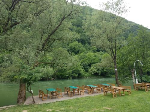 a row of tables and benches next to a river at Camp Vrbas in Rekavice