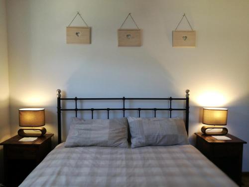een slaapkamer met een bed met twee lampen aan beide zijden bij The Lonely Oak Cottage in Szypliszki