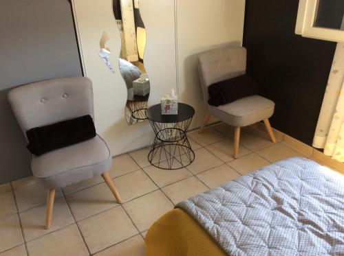 a bedroom with two chairs and a table and a bed at Le Claouraous calme in Canet